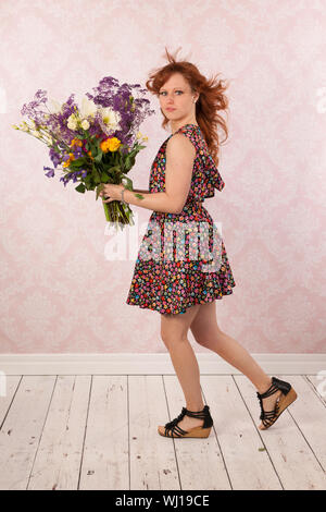 Frau im Innenraum mit bunter Strauß Blumen Stockfoto