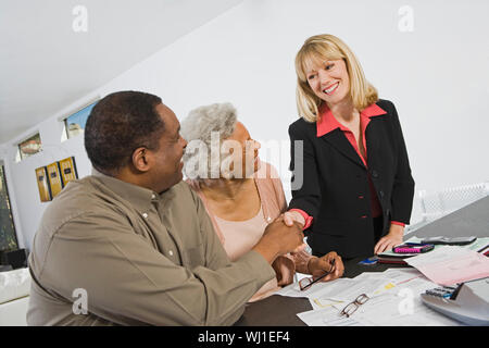Senior Paar Hände schütteln mit Finanzberater zu Hause Stockfoto