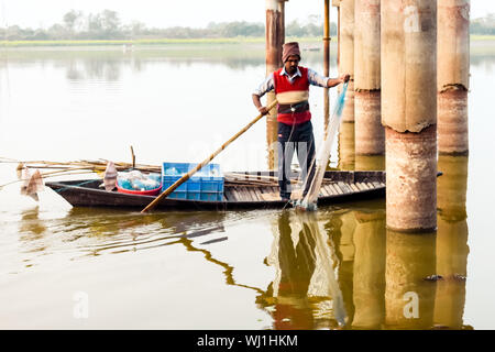 Kerala, Indien, 10. Januar 2018 - Ein einheimischer Fischer fischen mit seinem fischernetz auf einem Boot zu einem Kerala Backwater Bereich bei Sonnenuntergang Dämmerung. Stockfoto