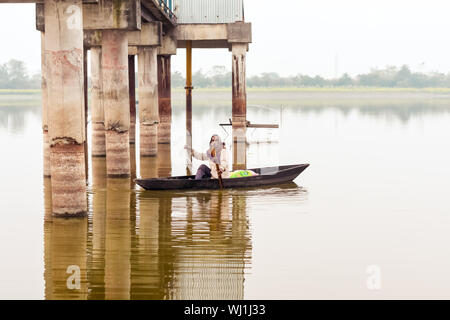 Kerala, Indien, 10. Januar 2018 - Eine lokale Active Senior Mann rudern sein Boot vom Ufer zu einem Kerala Backwater Bereich auf Sonnenuntergang Dämmerung. Stockfoto