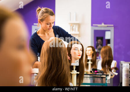 Hübschen weiblichen Friseur/Haidressing Lehrling/Student training auf einem Lehrling-Kopf Stockfoto