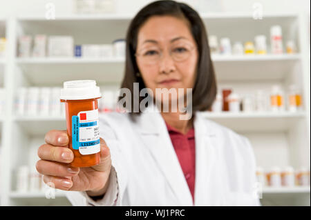 Portrait eines älteren weiblichen Apotheker holding Flasche Pillen am Arbeitsplatz Stockfoto