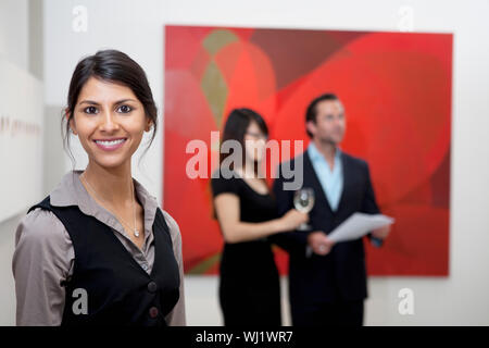 Portrait von lächelnden jungen Frau vor ein Paar im Museum Stockfoto