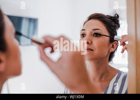 Junge Latina setzen auf Make-up vor dem Spiegel mit Ihrem Auge line Bleistift Stockfoto