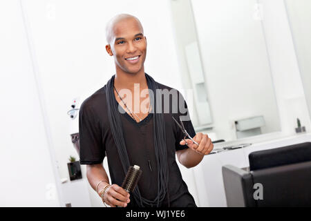 Lächelnd männliche Friseur Schere und Haarbürste holding Stockfoto