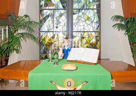Kleiner Junge stand der Altartisch Stockfoto