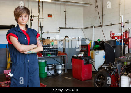 Porträt eines überzeugt junge weibliche Mechaniker mit Armen gekreuzt in garage Stockfoto