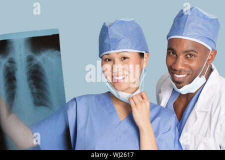 Porträt von glücklich Chirurgen Röntgen-Bericht über hellblauen Hintergrund halten Stockfoto