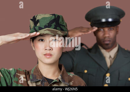 Porträt der jungen weiblichen und männlichen Marine Corps Soldat Offizier salutierte über braunen Hintergrund Stockfoto