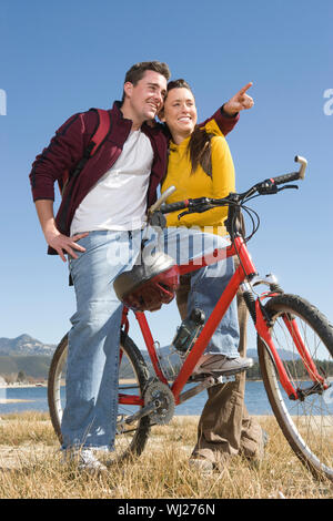 Volle Länge des glücklichen Mann auf dem Fahrrad mit Frau zeigt auf etwas Stockfoto