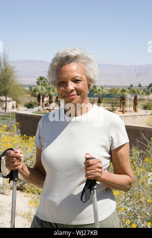 Portrait einer afrikanischen amerikanischen Senior woman holding Skistöcke in Park Stockfoto