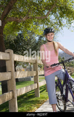 Porträt einer wunderschönen glückliche junge Frauen tragen Helm beim Radfahren im Park Stockfoto