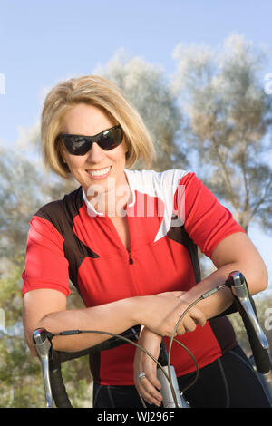 Portrait Of Happy weibliche Radfahrer lehnte sich auf dem Fahrrad Stockfoto