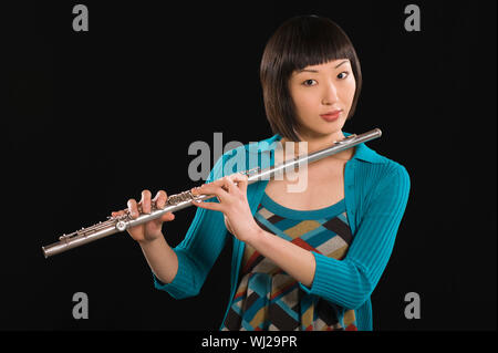 Porträt einer Frau mittleren Alters spielen Flöte über schwarzen Hintergrund isoliert Stockfoto