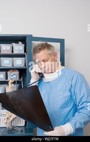 Älterer männlicher Arzt Analyse x-ray während der Kommunikation auf Festnetz Klinik Stockfoto