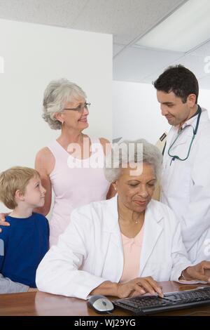 Eine leitende Ärztin mit Tastatur mit Patienten Beratung ihr Kollege in der Klinik Stockfoto