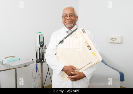Ein afrikanischer Amerikaner älterer männlicher Arzt in Klinik holding Dateien und Dokumente Stockfoto