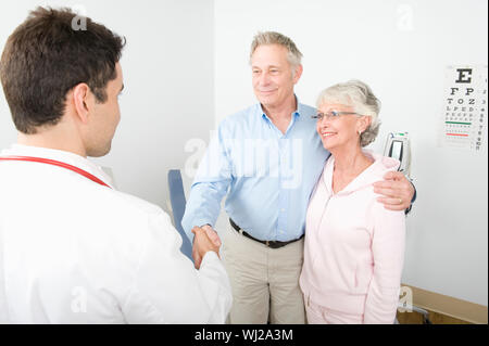 Ein dankbarer älterer männlichen stehen neben Frau Hände schütteln mit dem Arzt in der Klinik Stockfoto