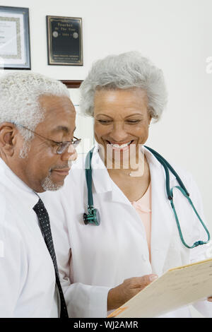 Zwei Afrikanische Amerikanische fröhlich Oberärzte auf ein Dokument in der Klinik Stockfoto