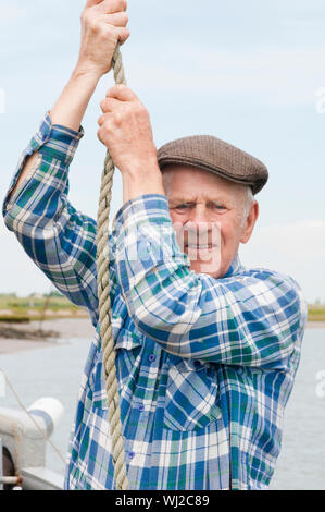 Closeup Portrait von ein alter Fischer schleppen das Seil im Boot Stockfoto
