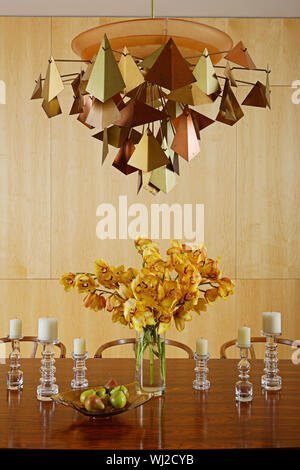 Metalworked Licht über dem Herzstück von Schnittblumen auf Tisch Stockfoto