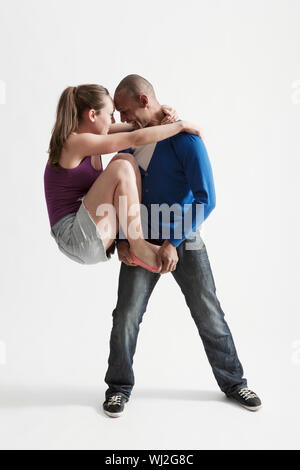 Volle Länge des jungen Mannes unterstützt moderne Tanz Partner auf weißem Hintergrund Stockfoto