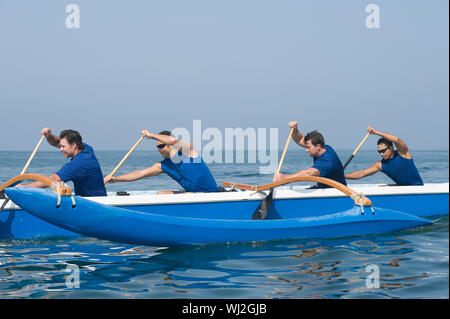 Seitenansicht der männlichen Ruderer paddeln Outrigger Kanu im Rennen Stockfoto