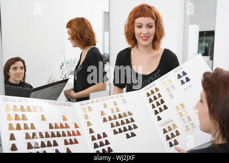 Weibliche Client und Friseur Auswahl Haarfarbe aus dem Katalog im Salon Stockfoto