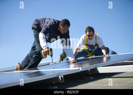 Zwei Ingenieure arbeiten an Solarzellen gegen den blauen Himmel Stockfoto