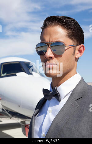 Hübscher junger Männer tragen Sonnenbrillen mit eigenem Flugzeug im Hintergrund Stockfoto