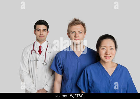 Porträt von zuversichtlich Multi ethnischen Ärzteteam stehen auf grauem Hintergrund Stockfoto