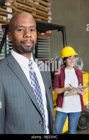 Porträt von zuversichtlich afroamerikanische männliche Geschäftsmann mit Arbeitnehmerin im Hintergrund stehen Stockfoto