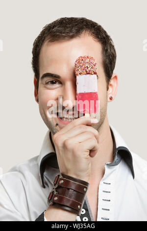 Close-up Portrait des jungen Mann, der Eisdiele vor grauem Hintergrund hält Stockfoto