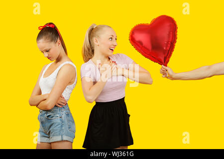 Hand des Mannes Herz verschenken geformte Ballon überrascht Frau mit Freund Gefühl hinter ausgelassen Stockfoto