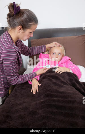 Mutter überprüfen Der unwohl Mädchen Temperatur zu Hause Stockfoto