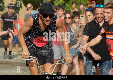 Aktion aus dem Radrennen, einer sehr kurzen bergauf Dash, in der Ortschaft Mianigues, Pla d'lestany, Girona, Spanien. Die Wettbewerber sind übergossen Fans. Stockfoto