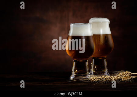 Zwei Gläser kalte dunkle Bier und Weizen ährchen auf dunklem Hintergrund. Kopieren Sie Platz Stockfoto