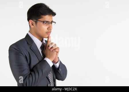 Seitenansicht der ein indischer Geschäftsmann denken mit seiner Hand am Kinn Stockfoto