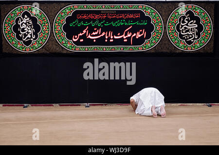 Ein gläubiger Muslim mann Bögen im Gebet vor der Koran Zitate an der Imam Al-Khoei Islamische Zentrum in Jamaica, Queens, New York City Stockfoto