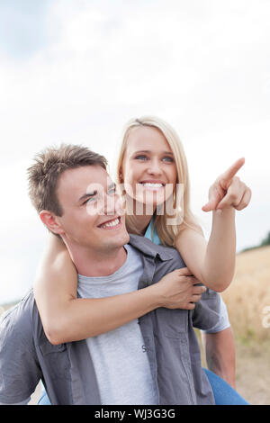 Schöne Frau, die etwas Menschen genießen Huckepack Ride im Feld Stockfoto