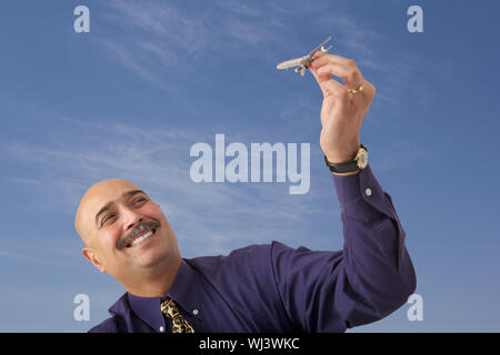 Geschäftsmann spielt mit Modellflugzeug und lächelt Stockfoto