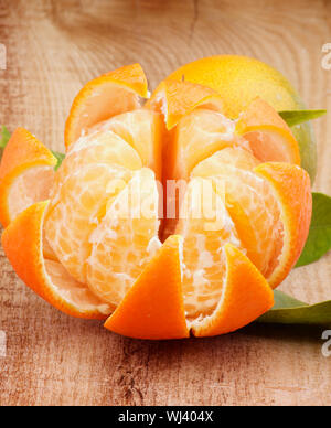 Frische reife Tangerine mit Segmenten und Schalen von Zitrusfrüchten closeup auf Holz- Hintergrund Stockfoto