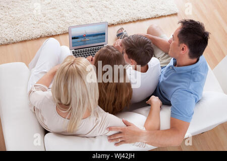 Eine glückliche Familie mit zwei Kindern sitzen auf einem Sofa mit Laptop zu Hause Stockfoto