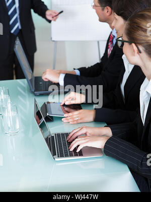 View-Bild aus einer Reihe von Geschäftsleuten auf Laptops und Tablets beschnitten während einer Präsentation oder Tagung Stockfoto