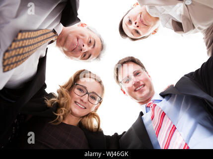 Niedrigen Winkel Ansicht von vier verschiedenen Führungskräften schaut in die Kamera von oben isoliert auf weiss Stockfoto