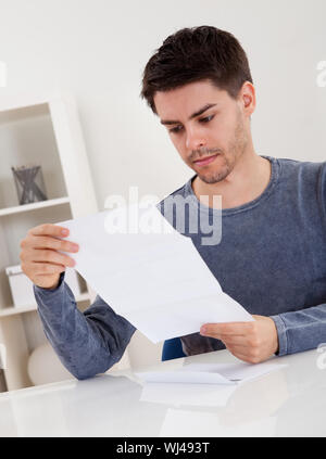 Jubelnder junger Mann Jubel bei gute Nachricht, die er nur in einem Dokument erhalten hat, die er liest Stockfoto