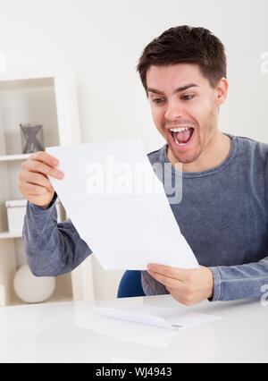 Jubelnder junger Mann Jubel bei gute Nachricht, die er nur in einem Dokument erhalten hat, die er liest Stockfoto