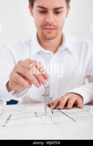 Closeup abgeschnitten Bild eines jungen männlichen Architekten arbeiten auf Blaupausen auf einem Tisch ausgebreitet Stockfoto