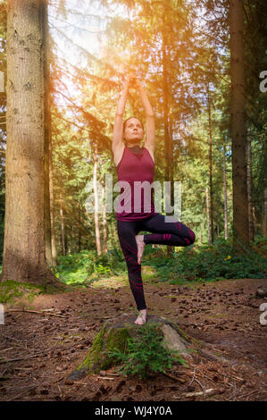 Frau, die in einem Wald ein Baum yoga dar. Stockfoto