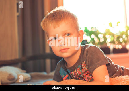 Ein niedliches 5jähriger Junge, wachte nach einem Nickerchen. Porträt einer verschlafenen Kind bei Sonnenuntergang. Das Konzept der Rest. Stockfoto